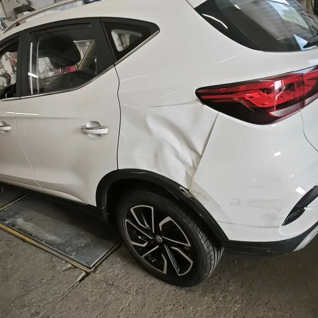 Weißer SUV mit eingedrückter hinterer Tür und Kotflügel in der Werkstatt