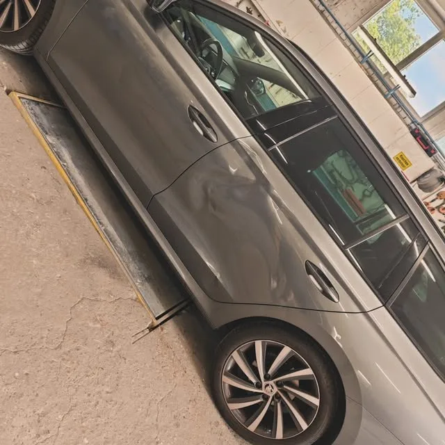 Grauer Wagen in Seitenansicht in der Werkstatt, über der Grube