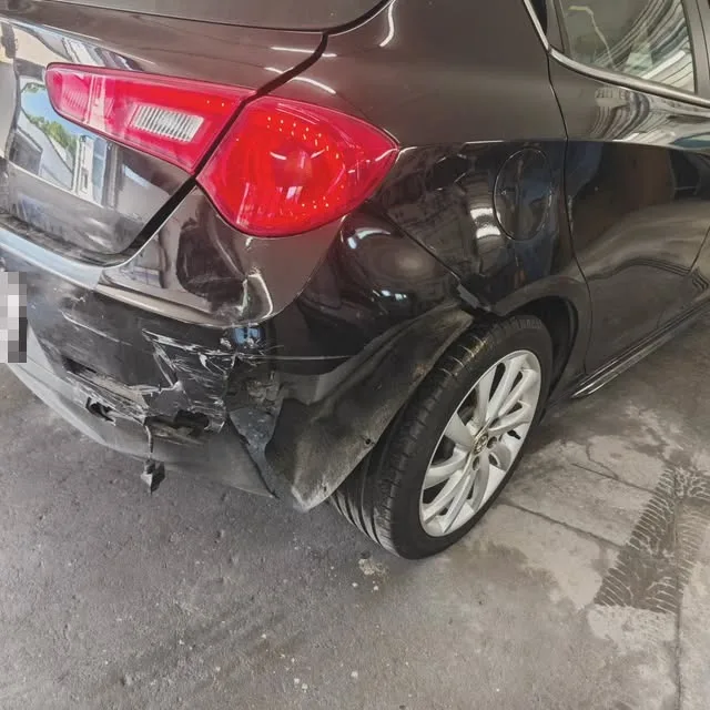 Dunkler Wagen mit Unfallschaden am hinteren Kotflügel und an der Stoßstange, in der Werkstatt