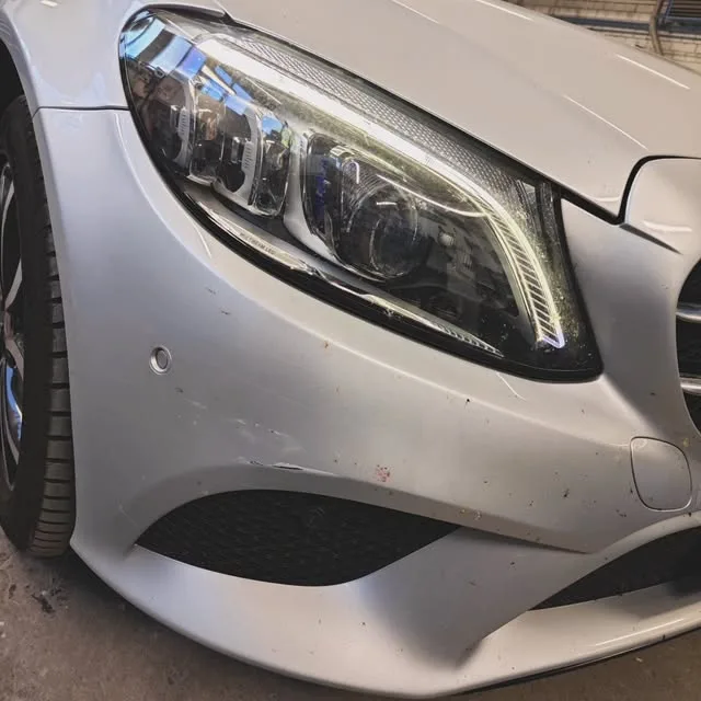 Front eines silbernen Mercedes mit Scheinwerfer, in der Werkstatt